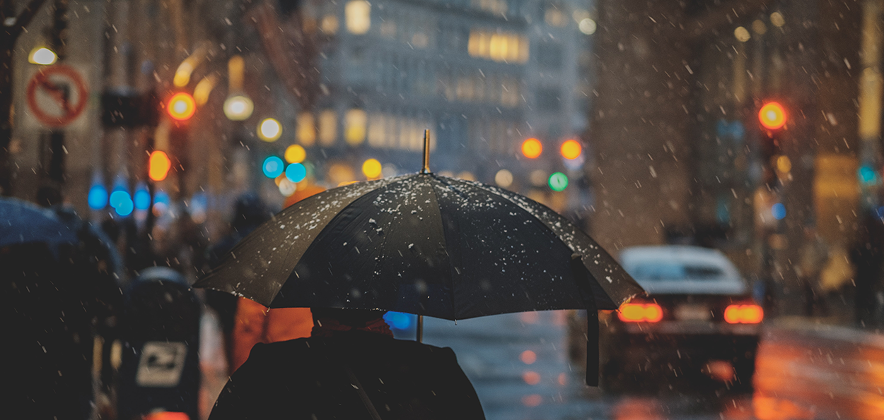 Person med paraply i oväder i stadsmiljö